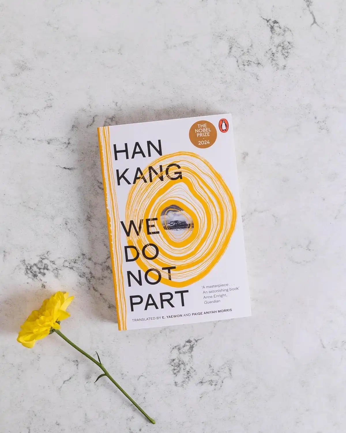 Books and You paperback edition of We Do Not Part by Han Kang with a yellow spiral cover design on a marble surface.